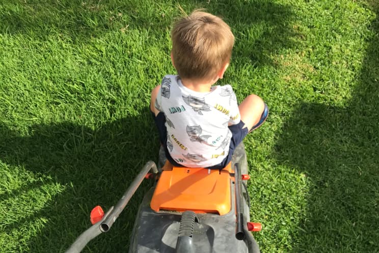 Arlo sitting on the lawnmower while mowing it